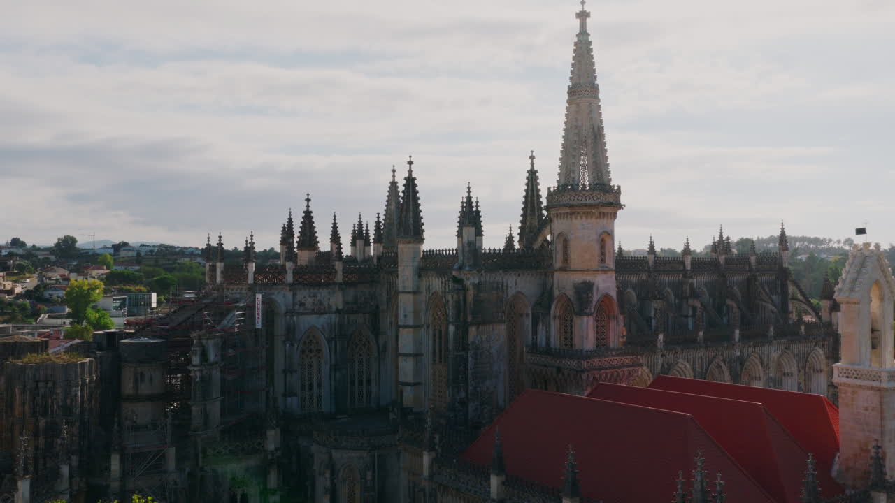 Mosteiro da Batalha aerial wide shot, slow forward drift over the monastery complex with cloisters visible and the town and hills in the background