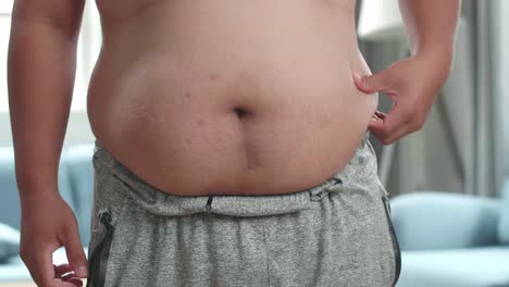 한 남자의 근접으로 그의 허리를 둘러싼 과도한 지방을 러
