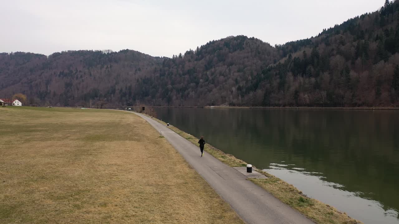 검은색 운동복을 입은 남자가 길을 걷는 동안 녹색 강과 갈색 초원이 이 클립을 장식합니다.