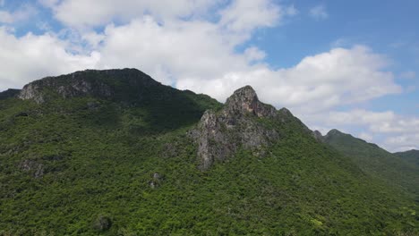 steady aerial footage of this gorgeous mountain and towers jutting out, white big clouds moving with blue sky