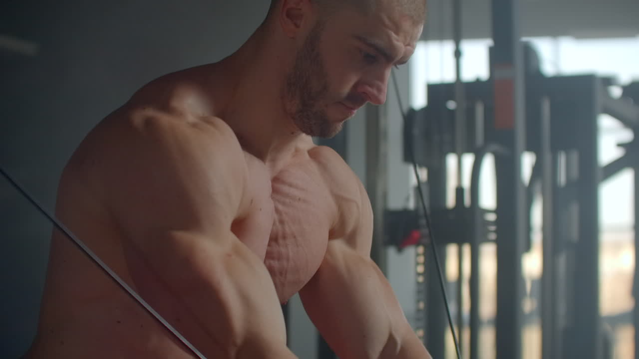 젊은이가 체육관에서 시레이터에서 손으로 절단합니다. 가 근육을 위한 운동. 크로스오버