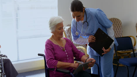 front view of caucasian female doctor and senior woman discussing over digital tablet at nursing hom