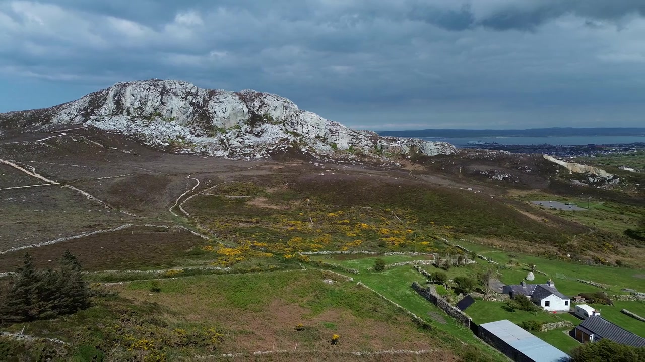 Onthullend luchtbeeld van Holyhead berg over een wandelpad door hooglandheide en een Solar vakantiehuisje.