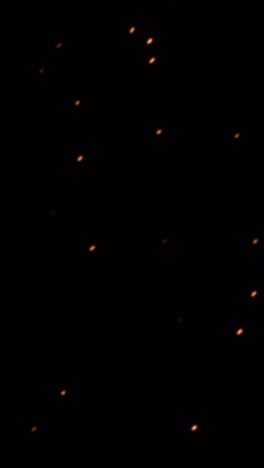 vertical shot of glowing embers lifting into the air from a source of fire
