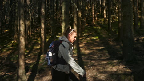 sporty adult woman hiking through a forest. slow motion