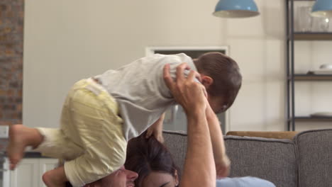 Parents-And-Son-Having-Fun-Playing-On-Sofa-Together