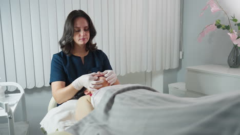 wellness therapist wearing gloves massaging mouth of female client on massage bed in spa room with white blinds and soft lamp lighting during relaxing facial therapy session showcasing expert care