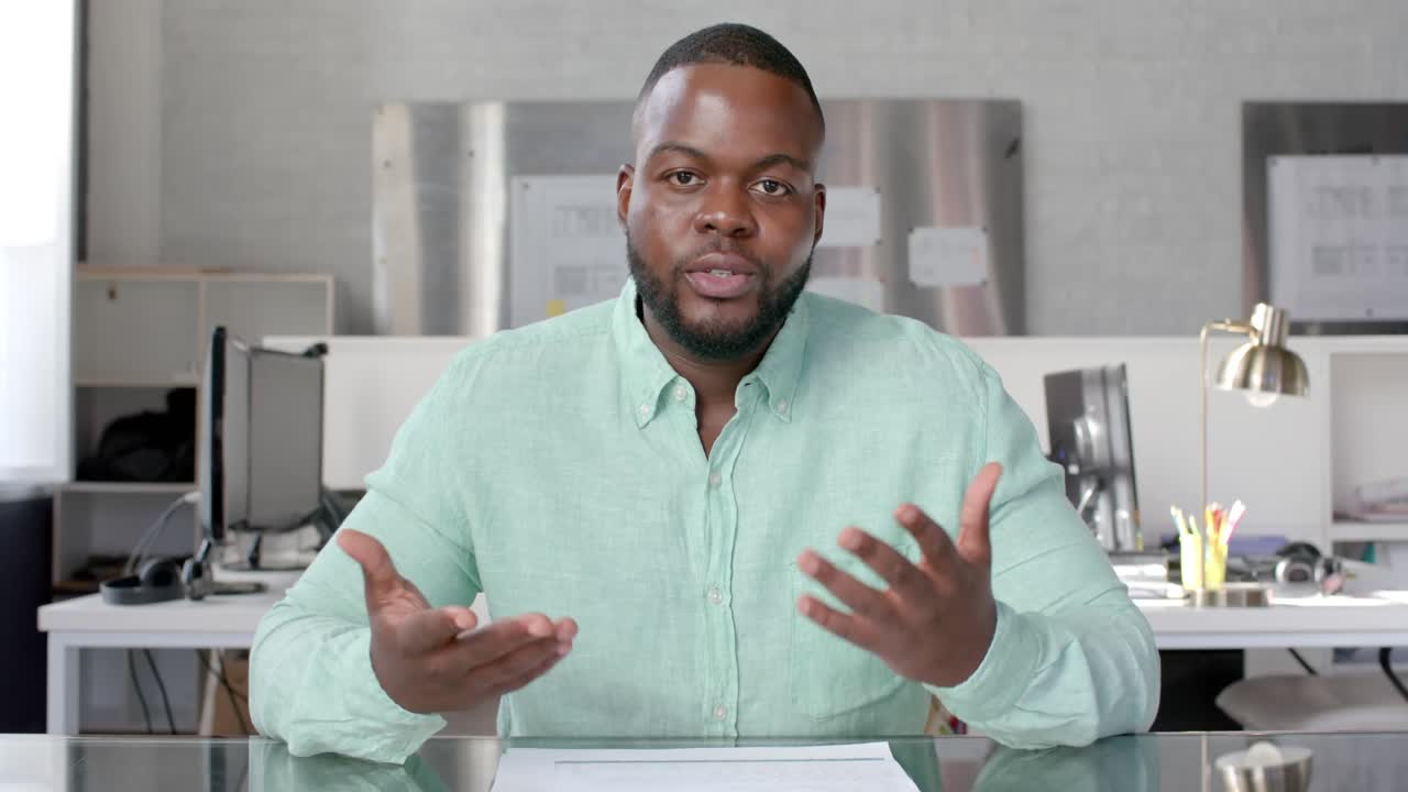 African american casual businessman having video call at office, talking and gesturing, slow motion