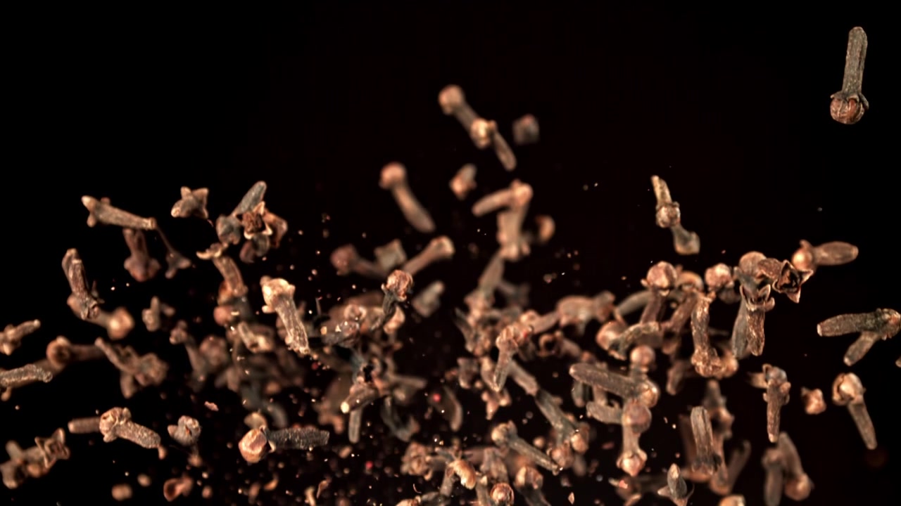 Dried Cloves Flying Up and Scattering on Black Background