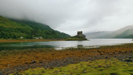 Low-Aerial-Flight-To-Eilean-Donan-Castle-Over-Loch-Duich-Shores,-Scottish-Highlands,-Scotland,-United-Kingdom