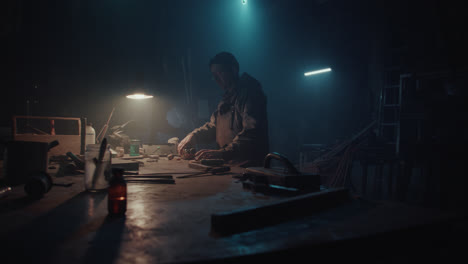 a bombmaker assembles a bomb in his workshop at night