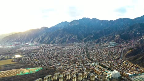 establishing aerial shot of jackson hole, near beijing, china. a chinese fake copy town inspired by the american town jackson in wyoming, usa. sunset with massive mountain range.