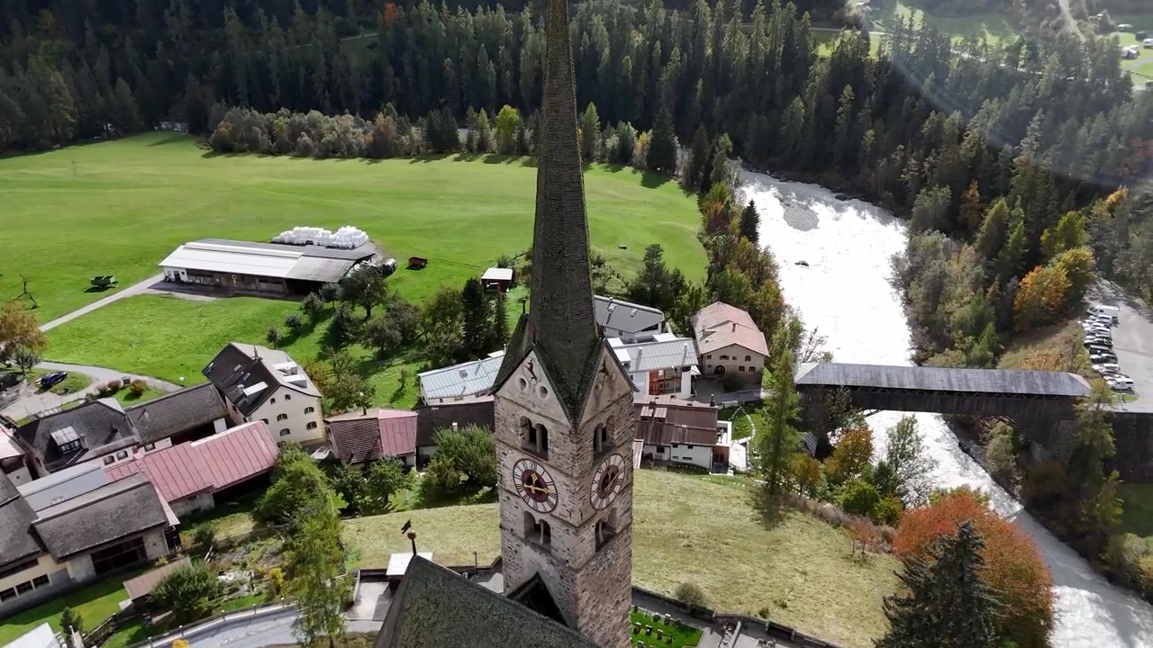 スクールにある、教会、川、そして周囲の森に囲まれた趣のあるスイスの村の空撮。