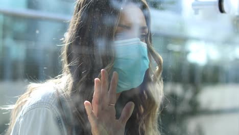 una mujer despejada con máscara está separada o aislada de un ser querido por una ventana de vidrio durante la pandemia de coronavirus 1