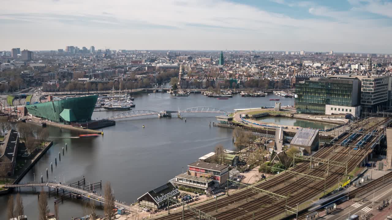 Timealapse video of the view over the Oosterdok area and historical city center of Amsterdam. Traffic, boats and trains can be seen passing by.