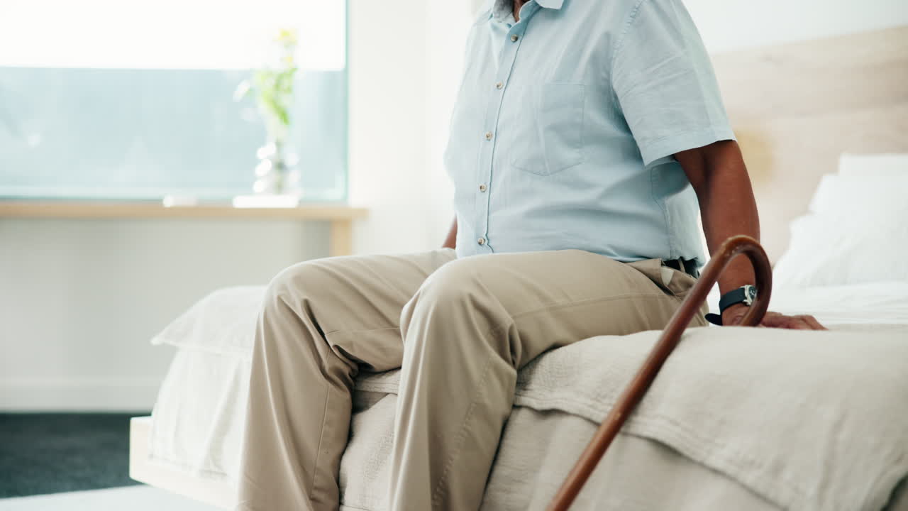 Elderly man sitting on bed with walking cane