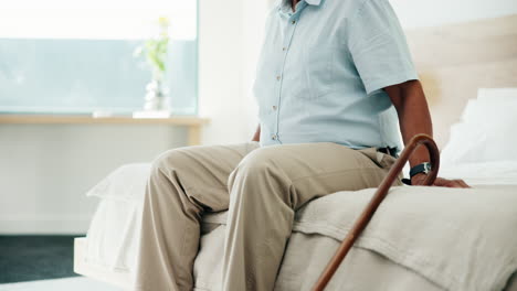 elderly man sitting on bed with walking cane