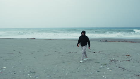 man holding a book walking alone near the sea in winter