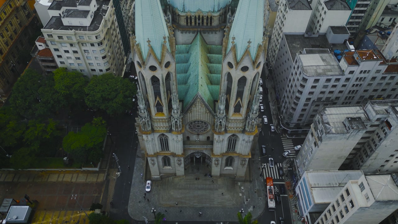 Stunning aerial drone footage of Catedral Metropolitana Nossa Senhora da Assuncao in Sao Paulo, Brazil. Gothic neo-Gothic cathedral towers with turquoise roof surrounded by urban cityscape.
