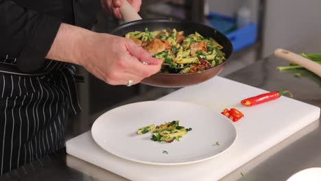 chef preparing a dish of penne pasta with chicken and pesto
