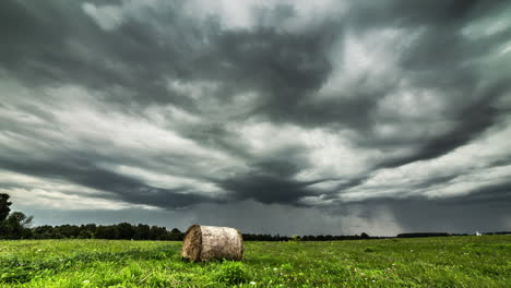 toma de lapso de tiempo de nubes grises oscuras volando en el cielo sobre un campo agrícola con fardos de heno