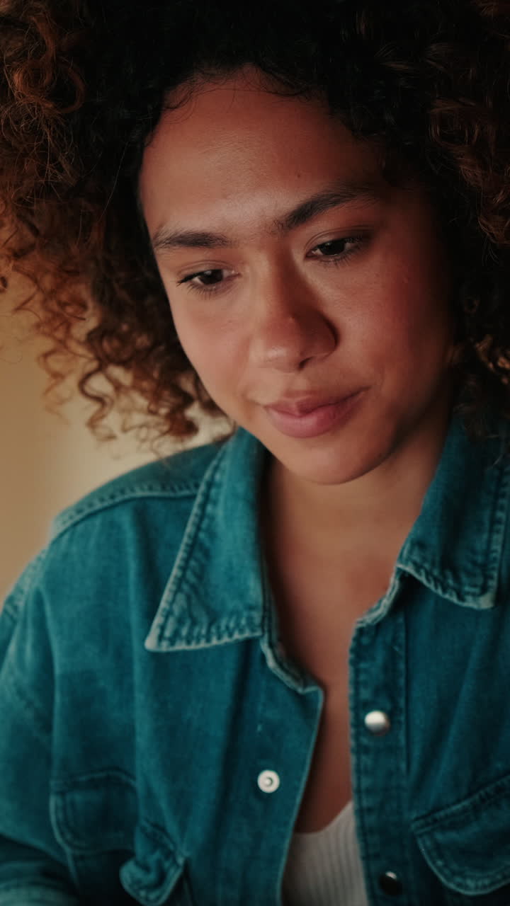 Close-up of a Young Woman with Curly Hair Looking Down Thoughtfully