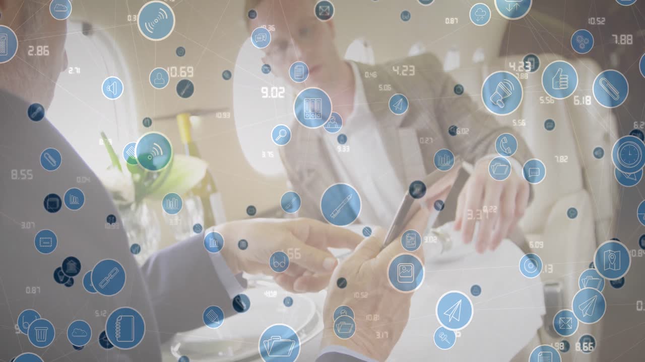 Animation of icons and numbers over caucasian entrepreneurs discussing reports in restaurant