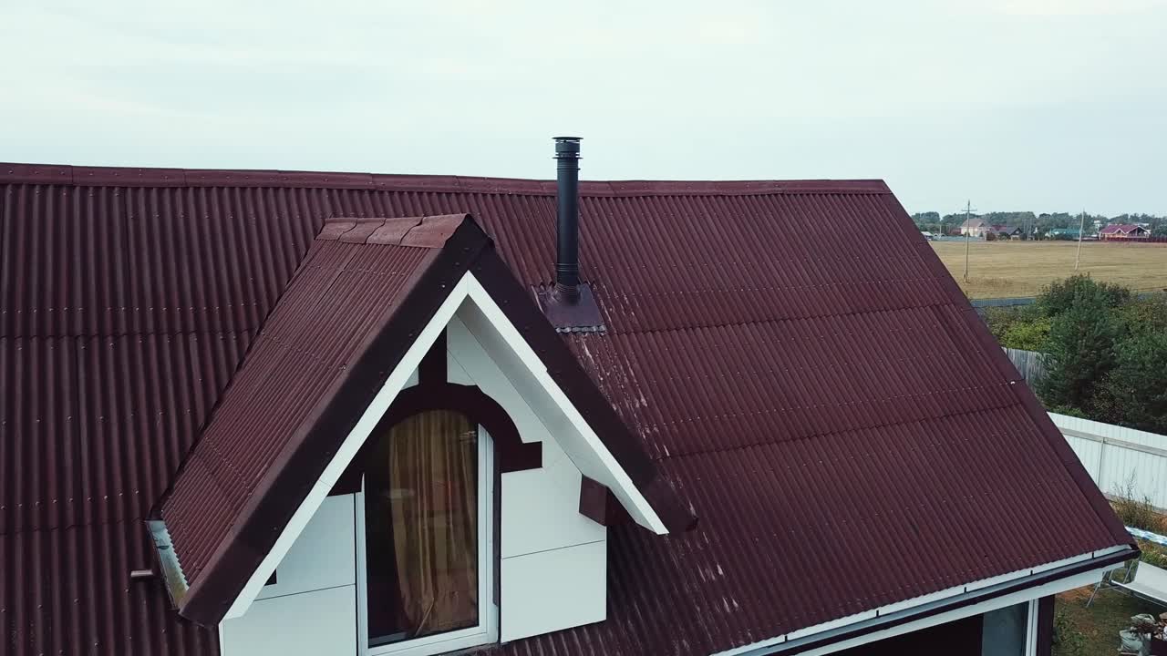 techo a dos aguas marrón con chimenea y ventana