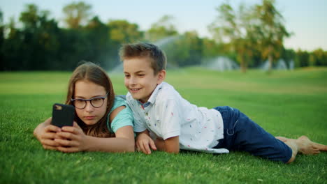 Hermano-Y-Hermana-Jugando-Juegos-En-El-Teléfono-Inteligente-En-El-Campo.-Niños-Usando-Teléfono-Móvil