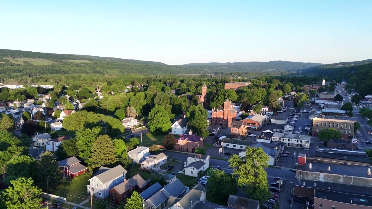 Sorvolo di drone che mostra la città di Watkins Glen vicino al Lago Seneca. Prospettiva dall'alto delle strade storiche del villaggio, dei quartieri residenziali e del paesaggio verde estivo.