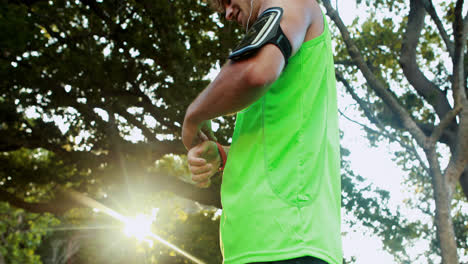 Man-tying-his-smart-watch-in-park