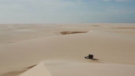 Antena:-Un-Camión-Con-Kitesurfistas-Viajando-A-Través-De-Las-Dunas-De-Lencois-Maranhenses-En-Brasil,-Durante-La-Estación-Seca