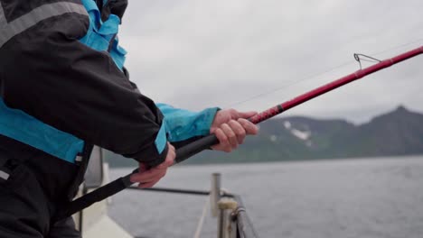 man on boat reeling fishing rod. - close up