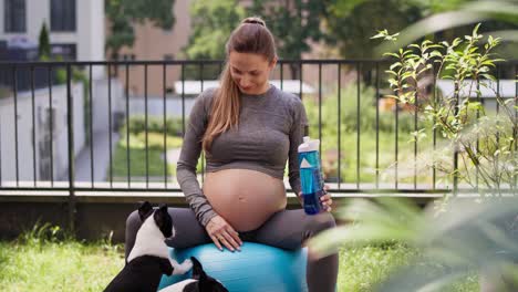 mujer embarazada descansando con perros después del ejercicio en el jardín