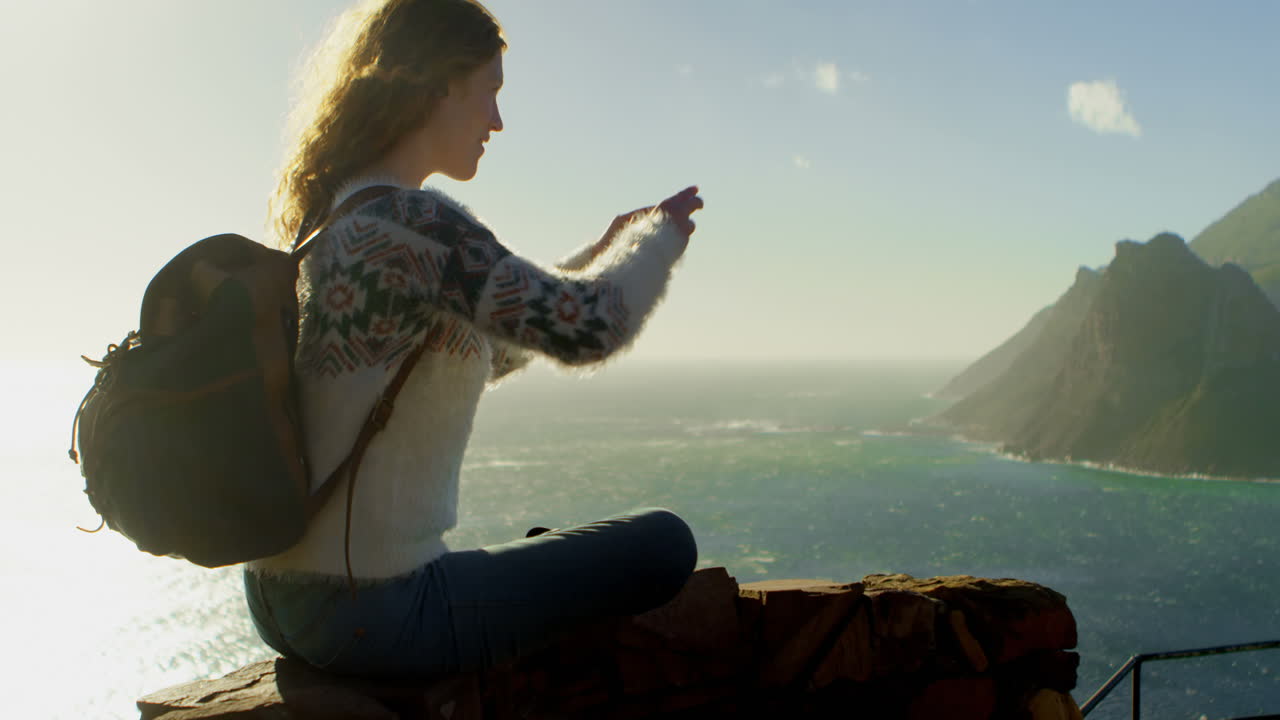 Donna che scatta foto con lo smartphone vicino al mare 4k