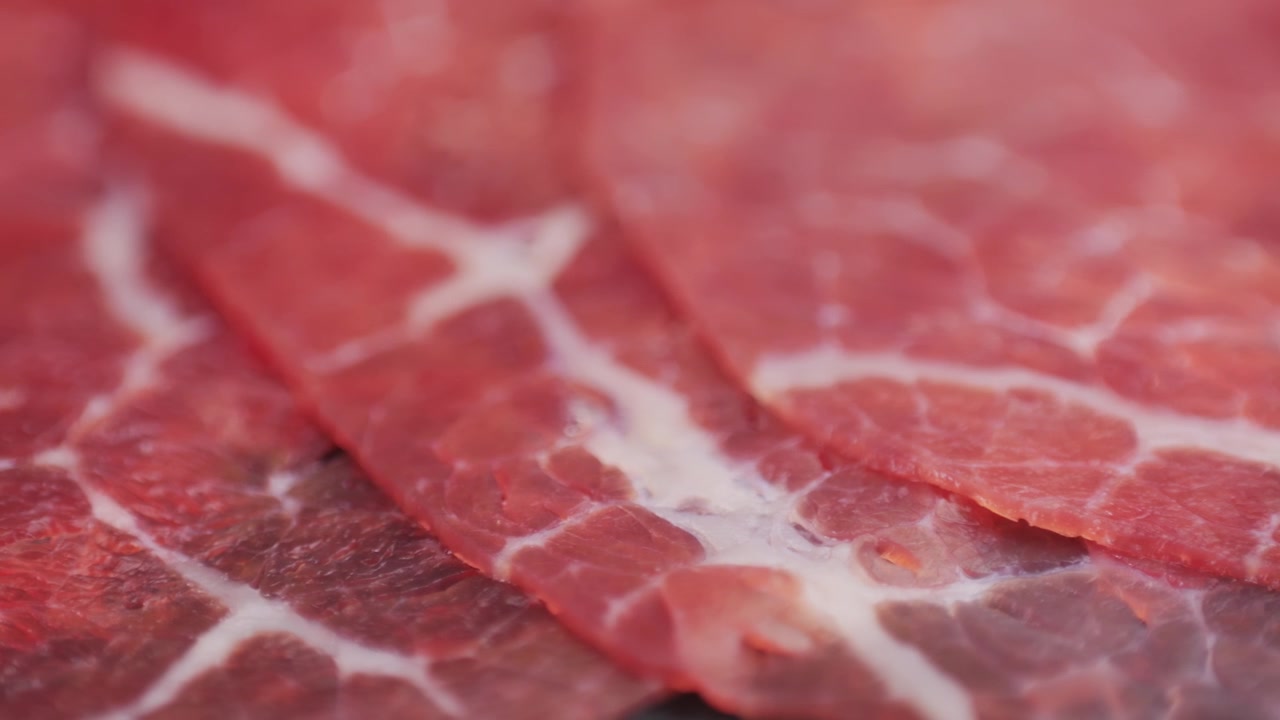 Primo piano di manzo crudo affettato sottilmente con marezzatura