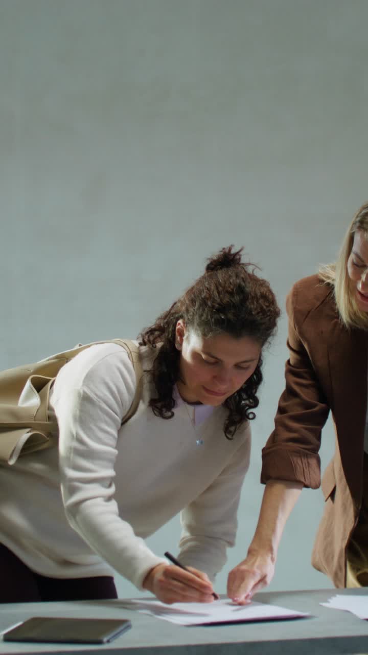 Two Women Signing Documents