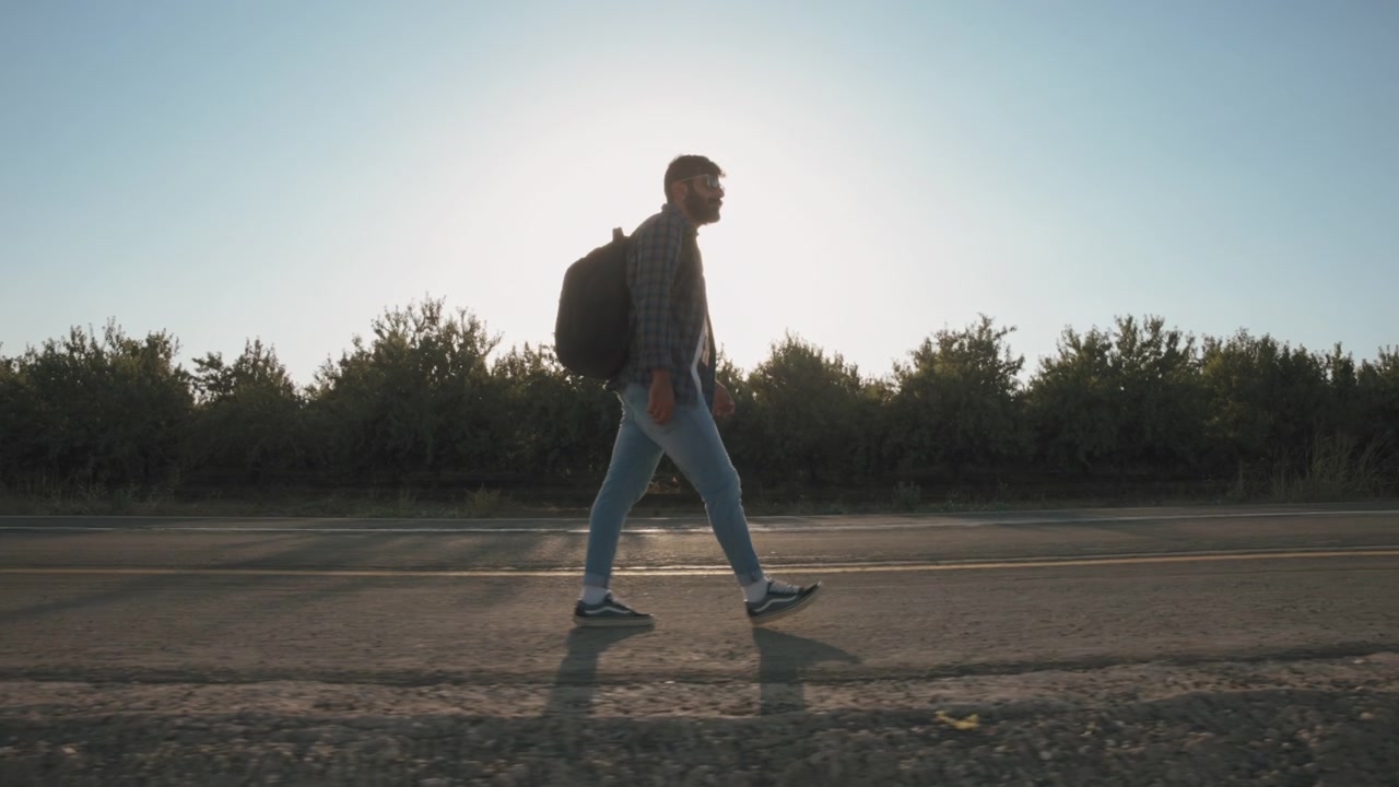 A bearded man walking on the road