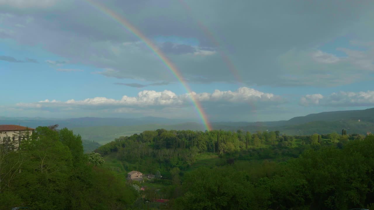 arco iris que termina su carrera en medio de los árboles de una colina en chianti. montepulciano