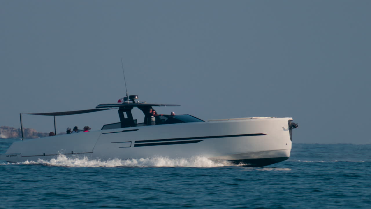 A sleek modern yacht speeds across the blue Mediterranean waters near the French Riviera