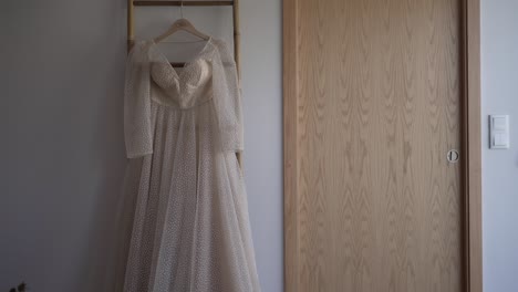 beautiful beige wedding dress hanging on a door