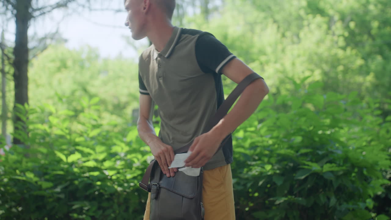 Young Man Worried, Youthful Man Anxiously Rummaging Through Bag Seeking Comfort And Relief, Young Man With Stressed Expression Frantically Searches His Shoulder Bag For Tissues And Calming Aid