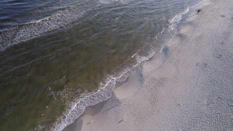 aerial drone flies over beach, sandbar as waves crash on the beach