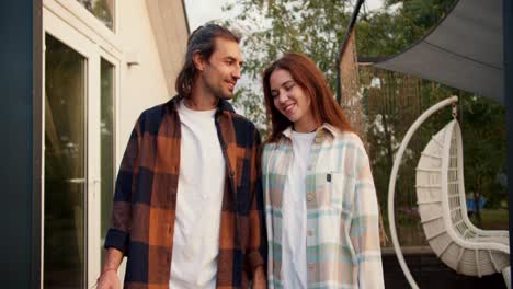 A-red-haired-girl-with-her-long-haired-brunette-boyfriend-in-a-white-checkered-shirt-are-walking.-Rest-in-the-country-house