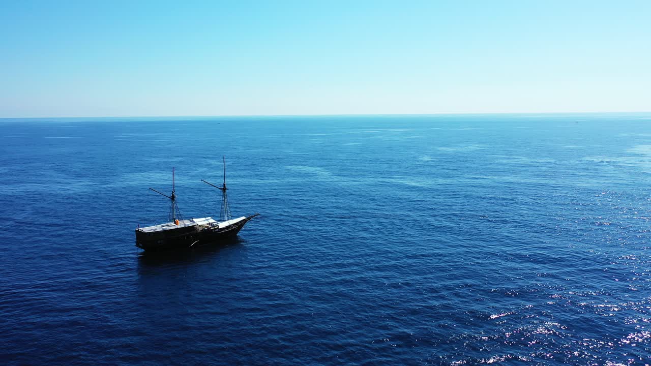 A large white and black ship alone in the middle of the beautiful blue waters of the ocean