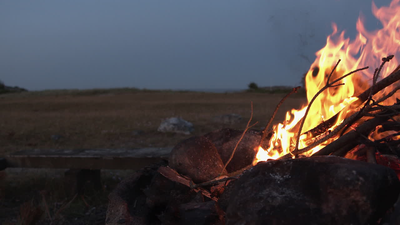 una acogedora hoguera ardiendo junto a un campo en cámara lenta