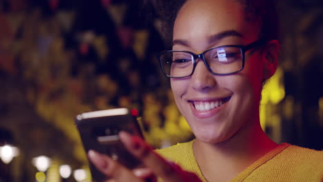 mujer sonriendo a su teléfono en la ciudad en