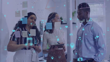 Animation of network of media icons over diverse casual business colleagues brainstorming at office