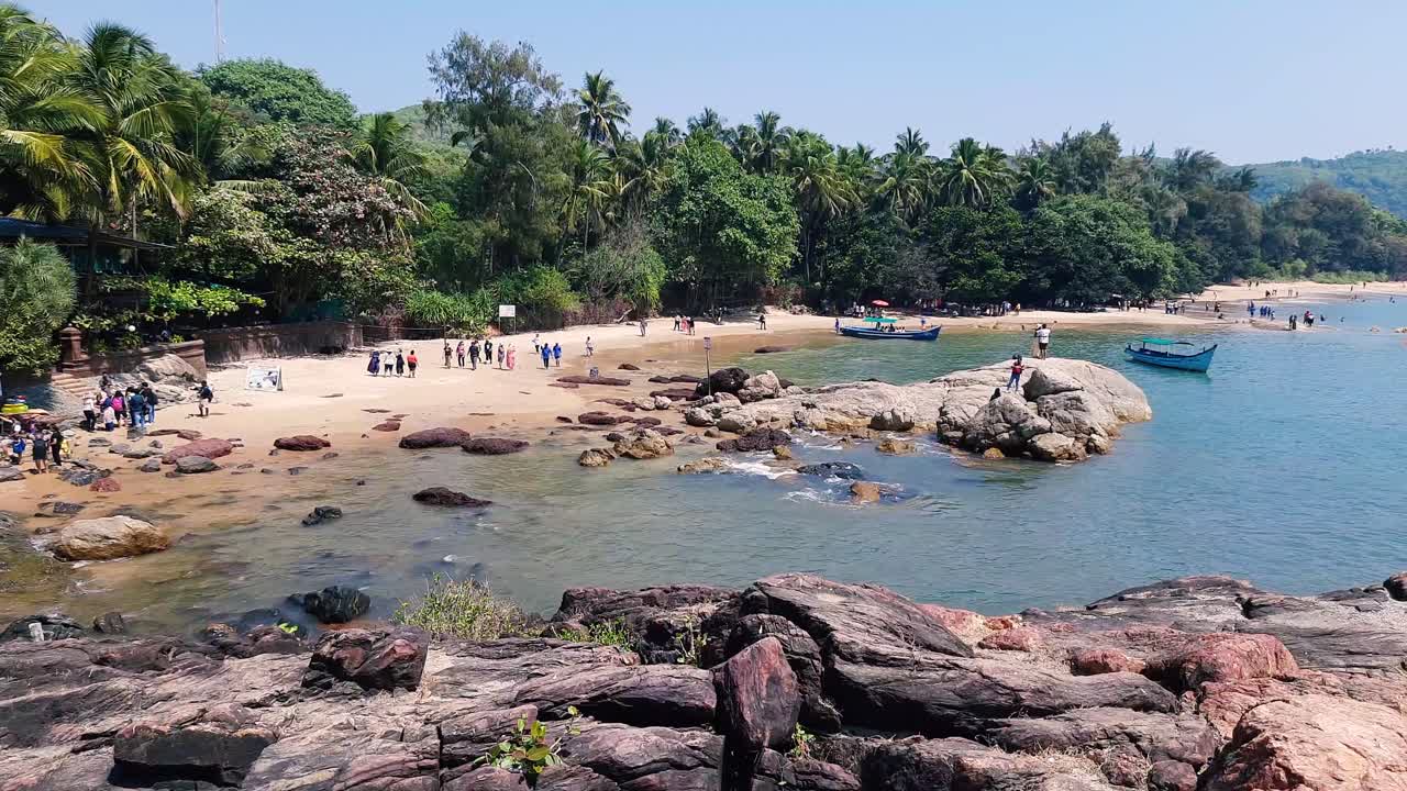 Inquadratura statica di persone irriconoscibili che si godono la spiaggia di Gokarna in una giornata di sole
