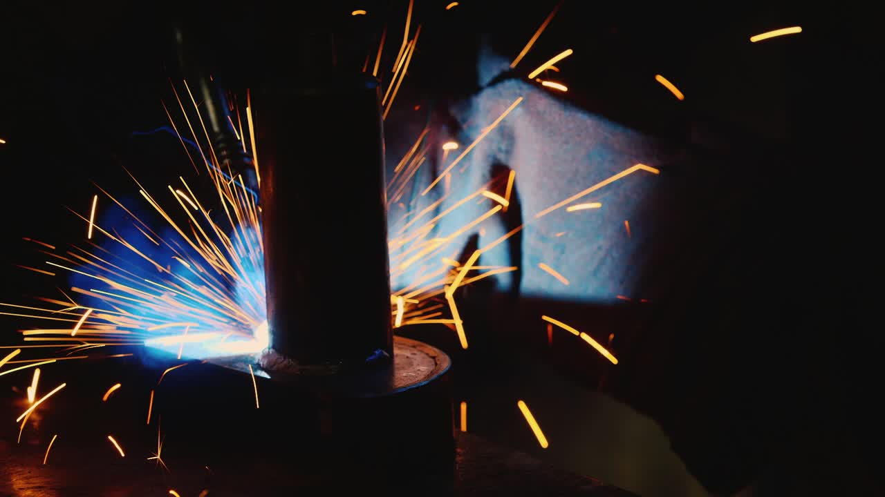 A welder in a protective helmet and clothes welds as sparks fly 2